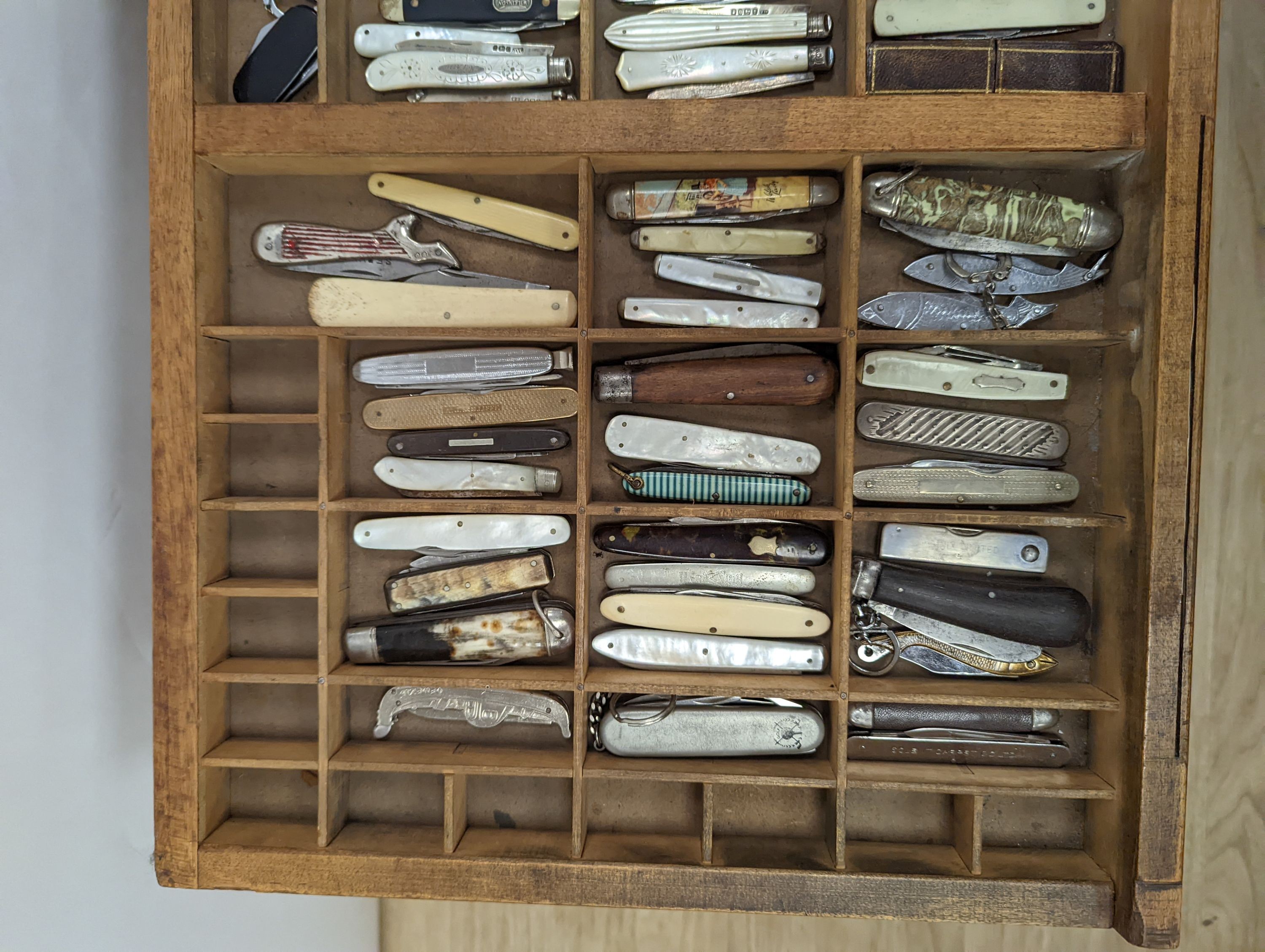 A collection of 19th century and later pen and fruit knives mounted in a coffee table